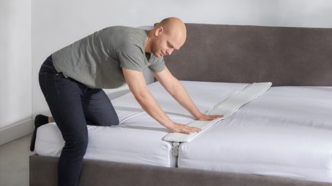 Een man die een bed opmaakt