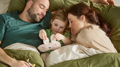 Een man en een vrouw die in bed liggen met een kind