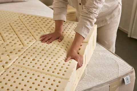 Iemand die een matras op een bed legt