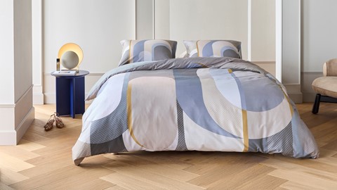 een bed met een beddengoed en een lamp