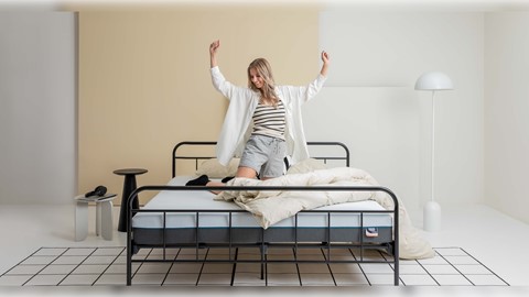 Een vrouw in korte broek en een wit shirt op een bed