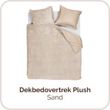 Een bed met een deken en kussens