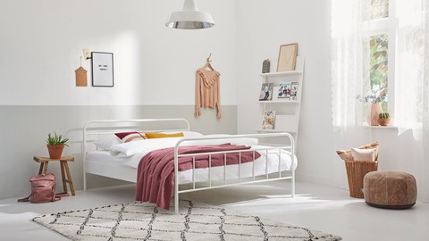 een witte slaapkamer met een bed en een kleed