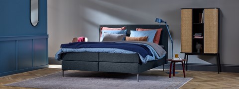 een bed met een blauwe deken en kussens