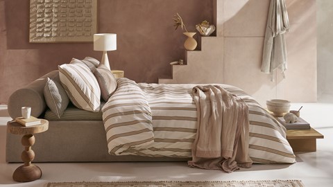 een bed met gestreepte lakens en kussens