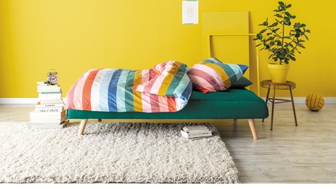 Een kleurrijk bed met kussens en een kleed