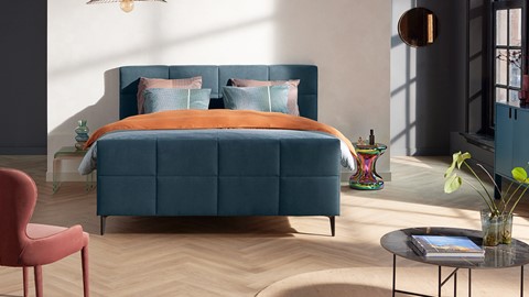 een bed met oranje en blauwe kussens