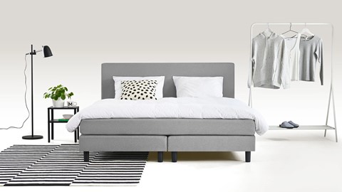 een bed met een bedframe en een rek met kleding