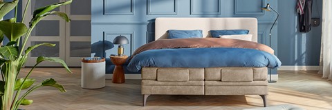 een bed met een blauwe deken en een tafel met een lamp