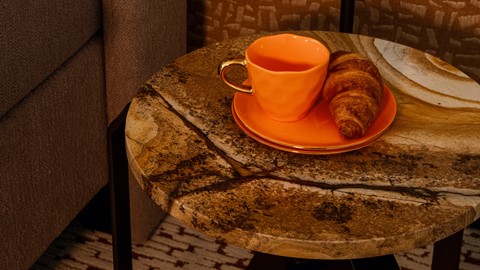 Oranje koffiekopje met croissantje op nachtkastje in hotelkamer