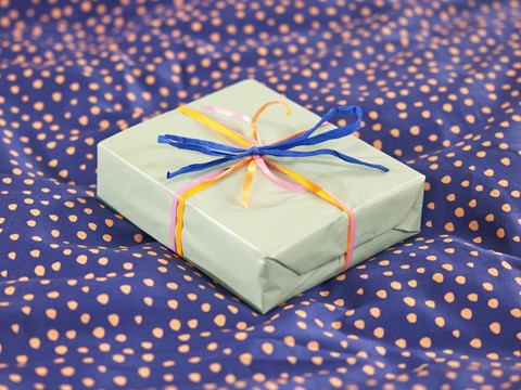 Een ingepakt cadeautje op een blauwe en roze stippenstof