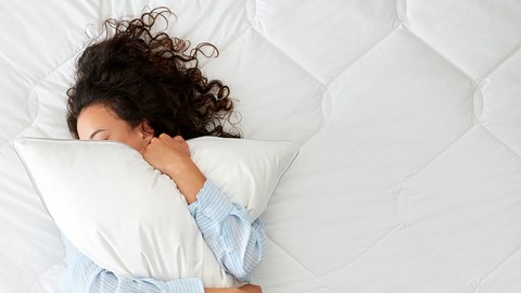 Een vrouw die op een bed ligt en een kussen koestert