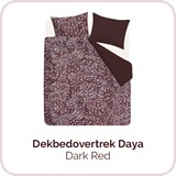 Een bed met een paarse deken en kussens