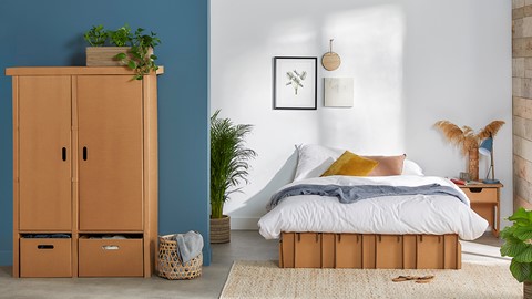 een bed in een kamer met een plant en een dressoir