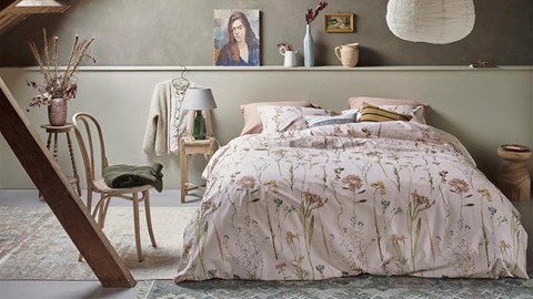 een bed met een bloemendekbed en een stoel