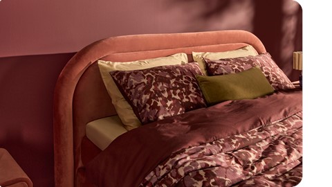 Een bed met een roze hoofdeinde