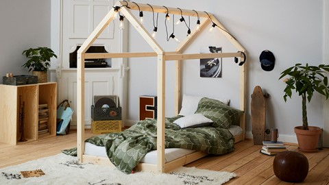 een bed met een huisvormig frame en verlichting