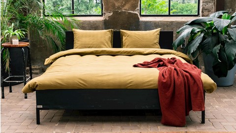 een bed met een deken en planten ervoor