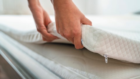 de handen van een persoon die een matras vasthouden
