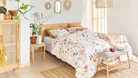 een bed met een bloemendekbed en een tafel met planten