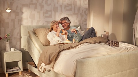 een man en vrouw zitten in bed te eten