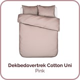 Een bed met een roze dekbed en kussens