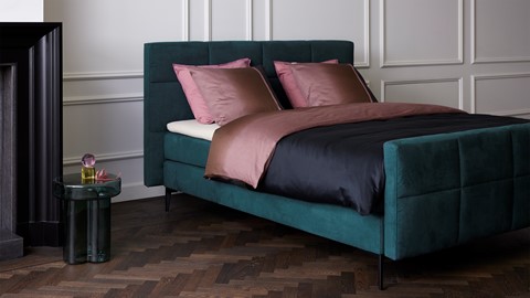 een bed met een roze deken en kussens in een kamer