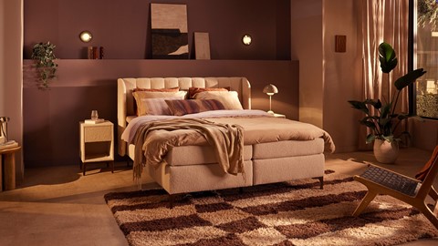 Een bed met een deken en een tapijt in een kamer