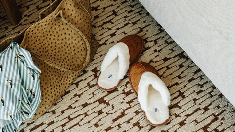 Pantoffels en slaaptas naast het bed in hotelkamer