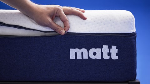 de hand van een persoon die een matras aanraakt