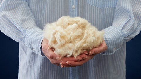 Een persoon die een stapel witte pluizige vacht vasthoudt