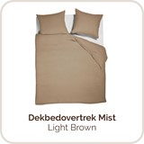 Een bed met een bruine deken en kussens