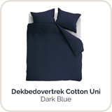 Een bed met een blauwe hoes en kussens
