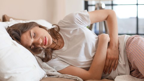 een vrouw liggend op een bed met haar handen op haar buik
