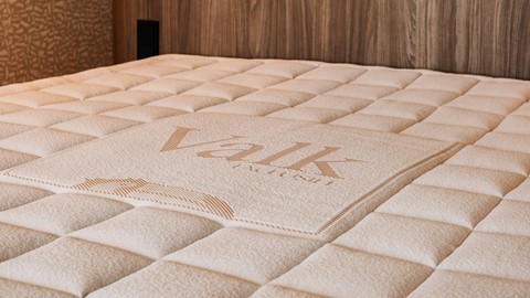 Valk Exclusief x M line topper op bed met Valk logo