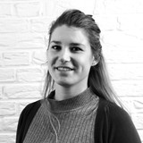 Een vrouw die voor een witte bakstenen muur glimlacht