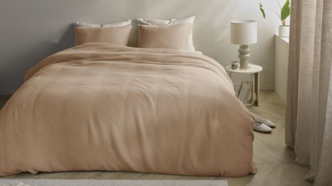 Een bed met een deken en een lamp