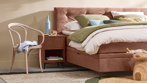 een bed met een bedframe en een stoel