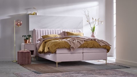 een bed met een roze hoofdeinde en een roze deken