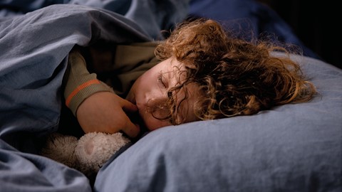 een kind dat in een bed slaapt met een knuffeldier