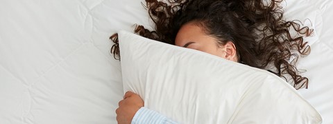 Een vrouw die in bed met een hoofdkussen ligt