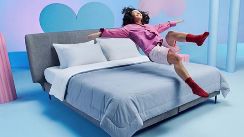 een vrouw die in de lucht springt op een bed