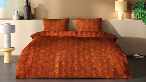 een bed met oranje dekbed en kussens