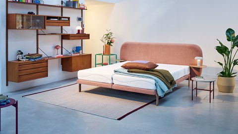 een bed met een roze hoofdeinde en kussens