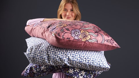 Een vrouw die een stapel kussens houdt