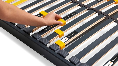 de hand van een persoon die een bedframe aanraakt