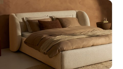 Een bed met bruine kussens