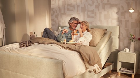 een man en vrouw zitten in bed te eten