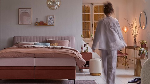 Een vrouw die in een slaapkamer loopt