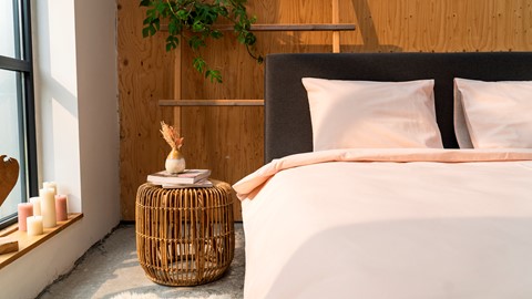 een bed met roze kussens en een mand met boeken